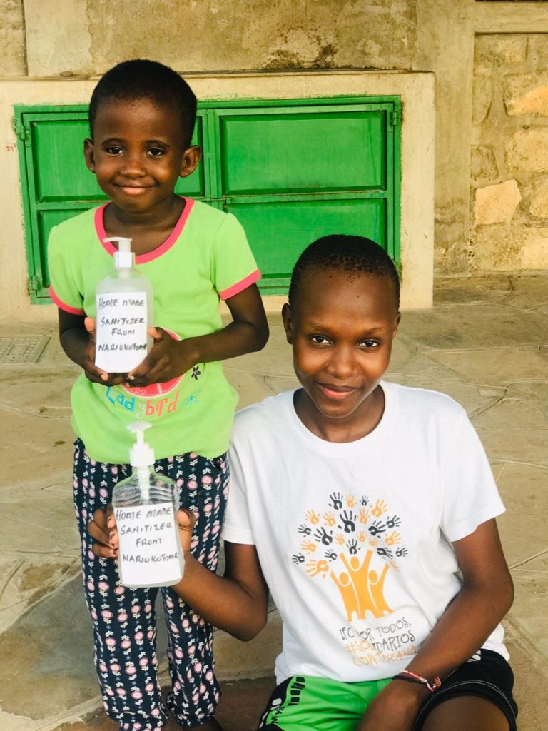 Geles Sanitizer: dos niñas de la misión de Nariokotome posando con frascos de sanitizer en las manos