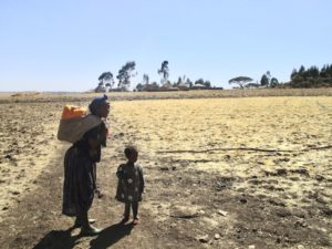 El rol de las mujeres en la gestión del agua: una madre con su hija caminando con un bidón de agua a la espalda